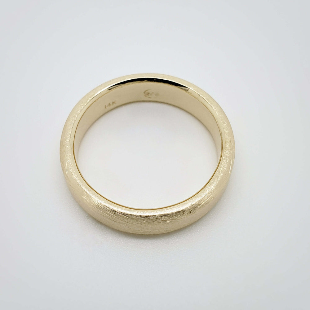 Top view of flat brushed 14k yellow gold wedding ring on white background