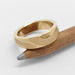 Topography textured yellow gold wedding ring displayed on a pencil
