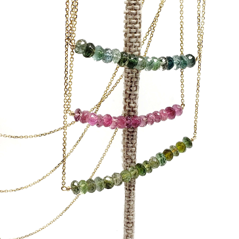 Tourmaline bead bar necklaces in teal, pink, and green on a display stand