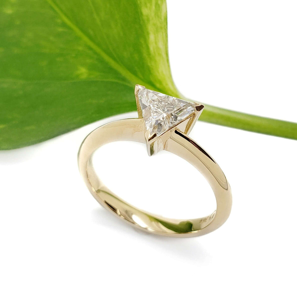 Triangle cut lab-grown diamond ring in yellow gold, shown with a green leaf background