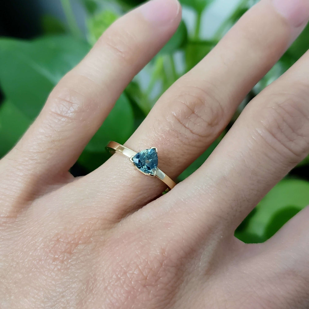 Trillion cut teal Australian sapphire ring in yellow gold, worn on hand