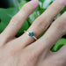 Trillion cut teal Australian sapphire ring in yellow gold, worn on hand