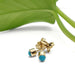14kt yellow gold turquoise stud earrings resting near a green leaf
