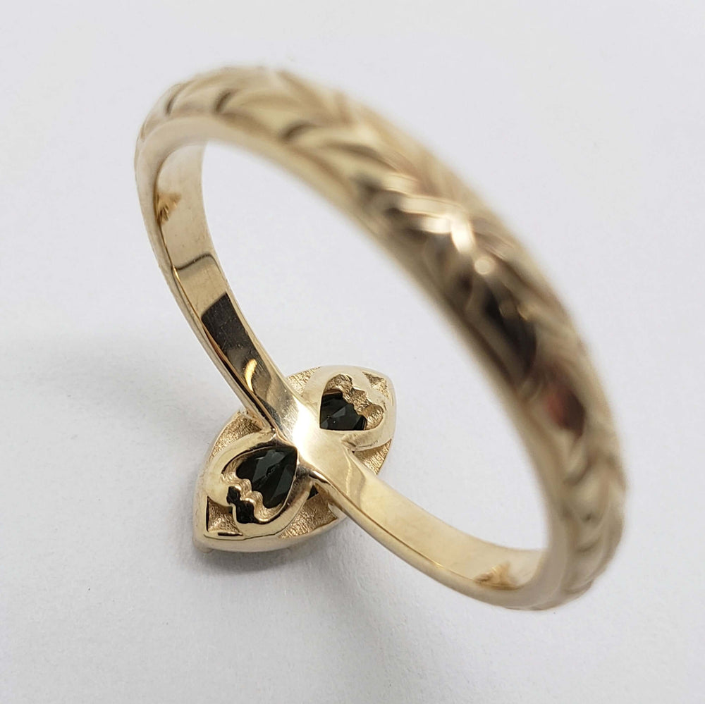 Underside of 14kt yellow gold ring showing marquise green sapphire and engraved detail