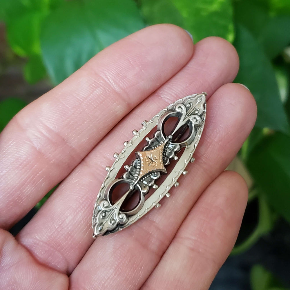 Victorian sweetheart pin in silver and rose gold shown resting on a hand