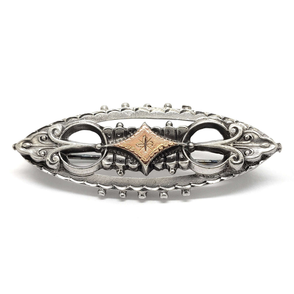 Victorian two-tone silver and rose gold pin with ornate scrollwork and engraved detail