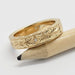 Vintage-inspired 14kt yellow gold diamond wedding ring with hand engraving, resting on pencil