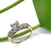 Vintage-inspired diamond engagement ring in 14kt yellow and white gold beside a green leaf