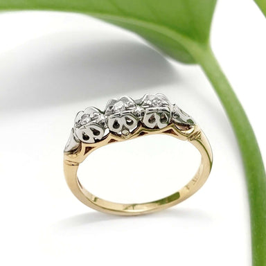 Vintage-inspired diamond wedding ring in 14kt yellow and 18kt white gold, shown beside a green leaf