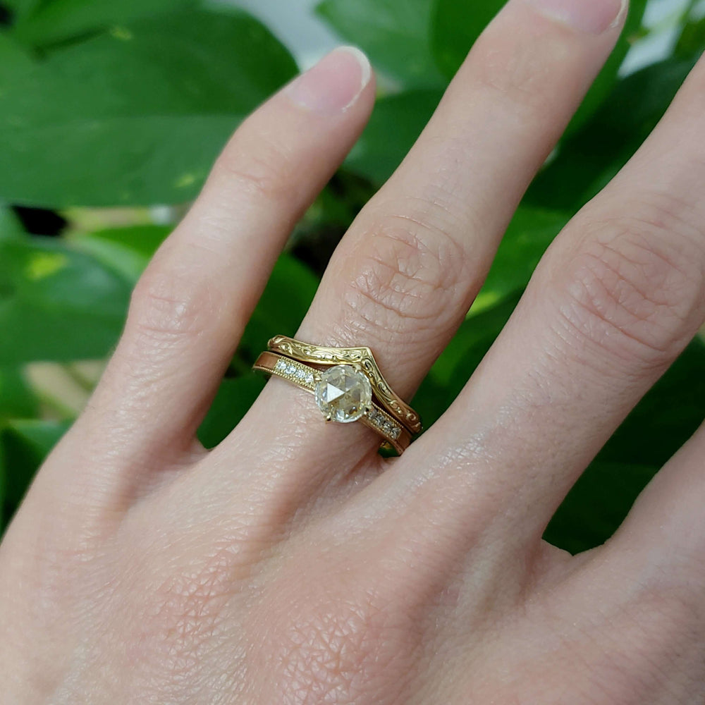 Vintage-inspired yellow gold lab diamond engagement ring stacked with engraved band
