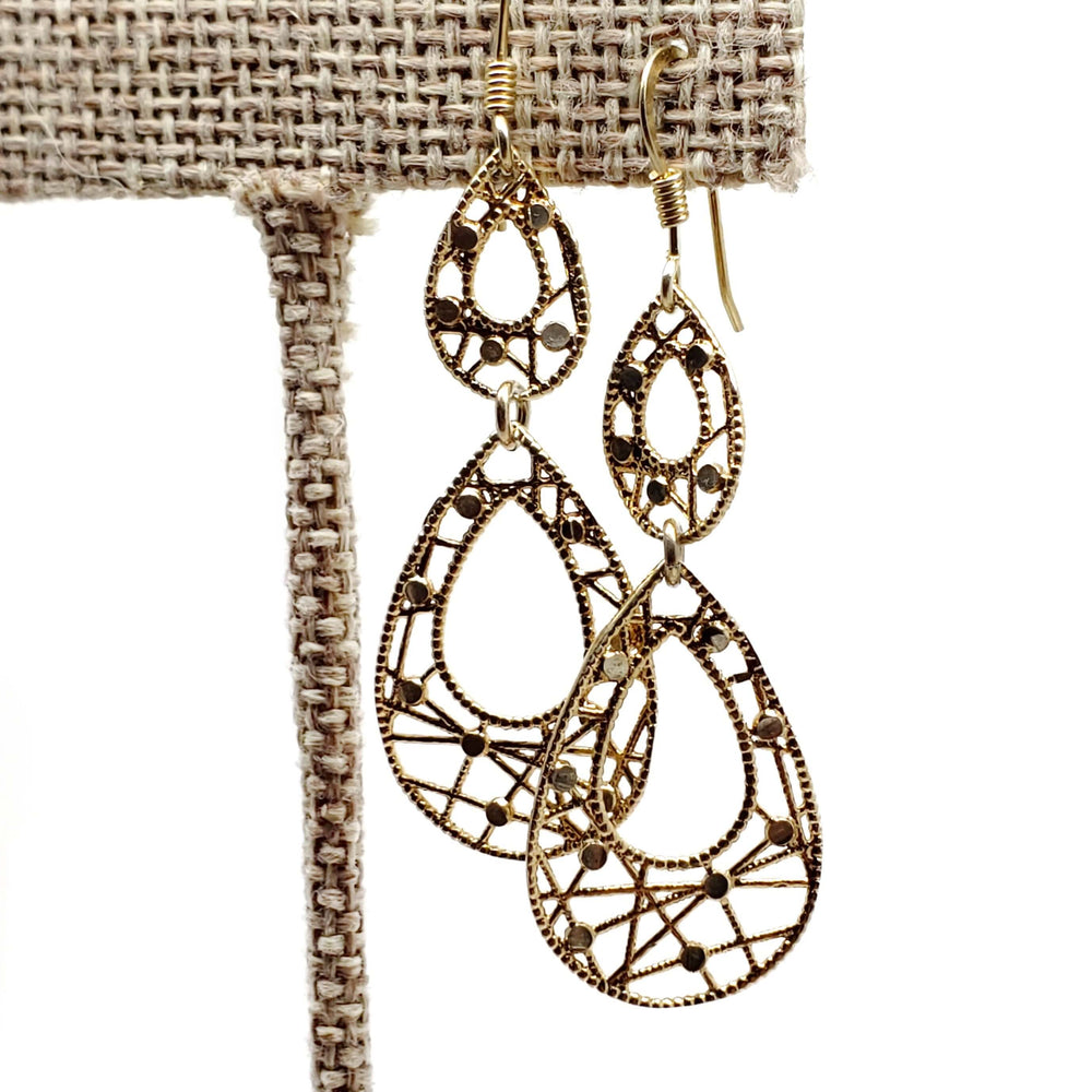 Vintage 10kt yellow gold filigree dangle earrings displayed on a fabric stand