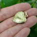 Hand holding vintage 14kt yellow gold heart locket with detailed engraving