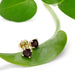 Vintage 14kt yellow gold red spinel stud earrings displayed on a green leaf