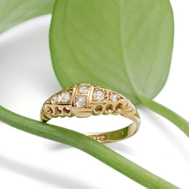 Vintage 18kt yellow gold diamond ring resting on green leaf