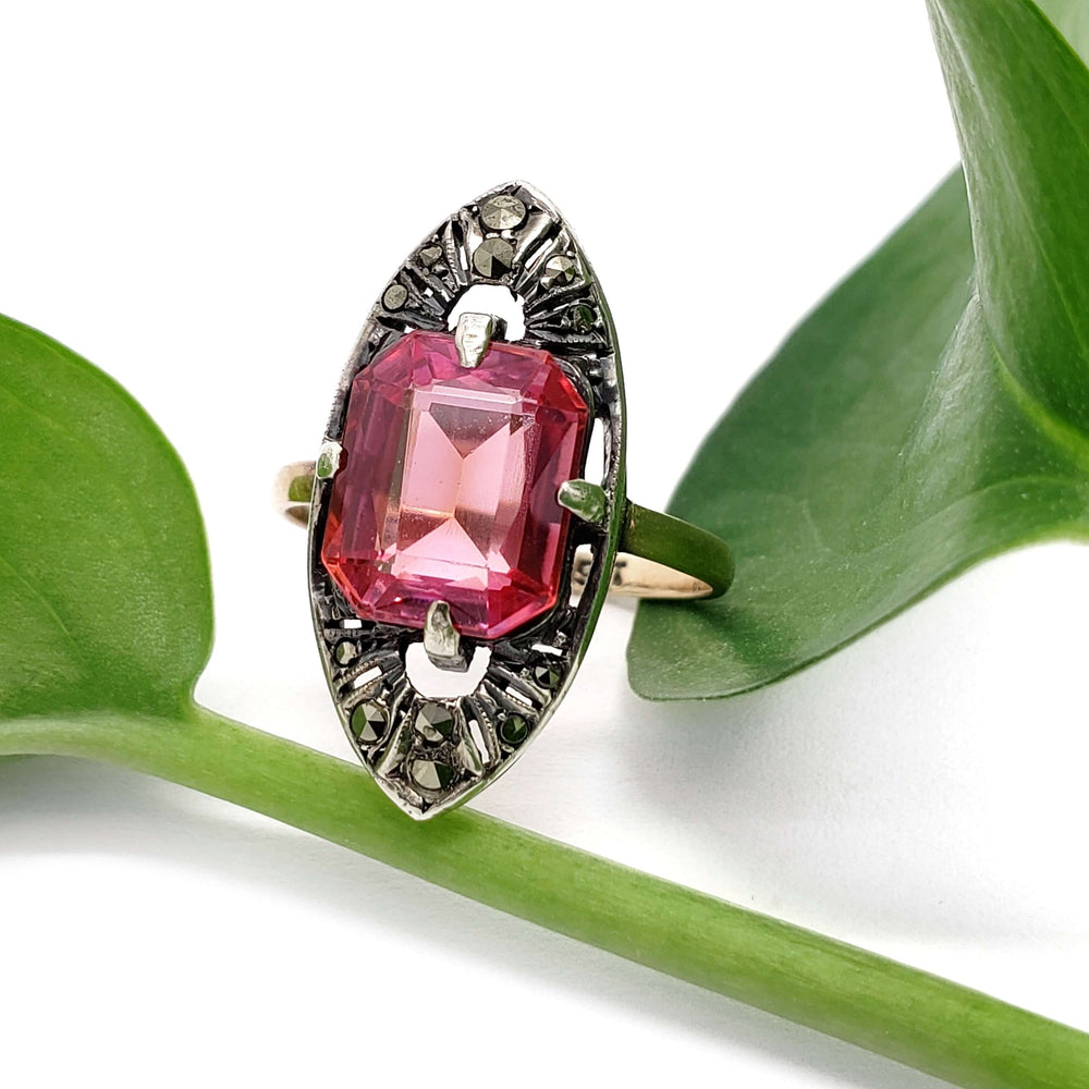 Vintage 9kt gold and silver ring with pink synthetic sapphire and marcasite, shown on green leaf