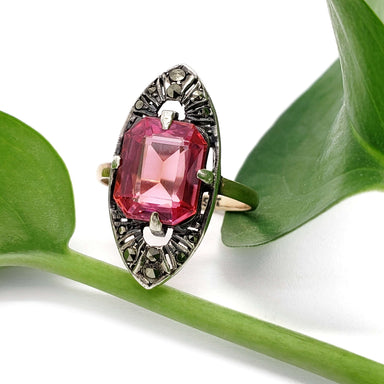 Vintage 9kt gold and silver ring with pink synthetic sapphire and marcasite, shown on green leaf