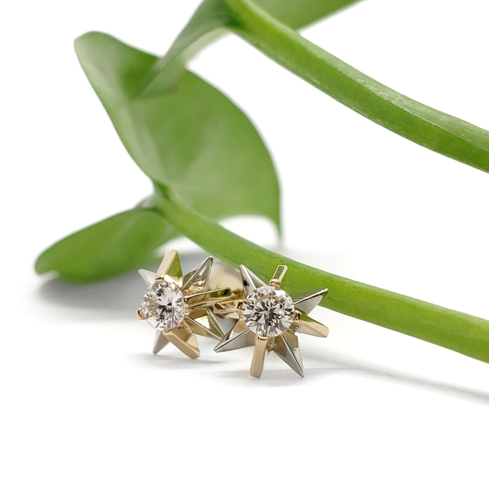 Vintage diamond starburst earrings in 14kt yellow and white gold displayed with green leaf