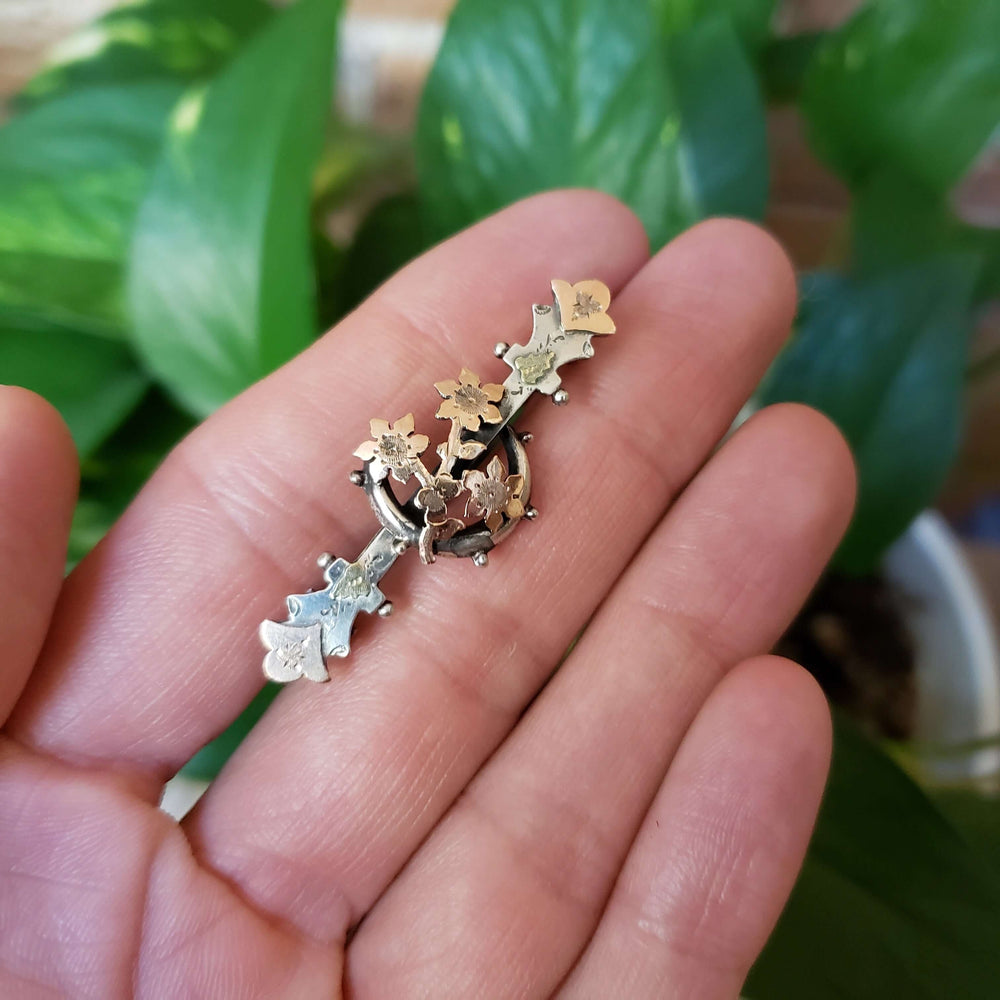 Vintage silver and rose gold moon flower pin displayed in hand for scale