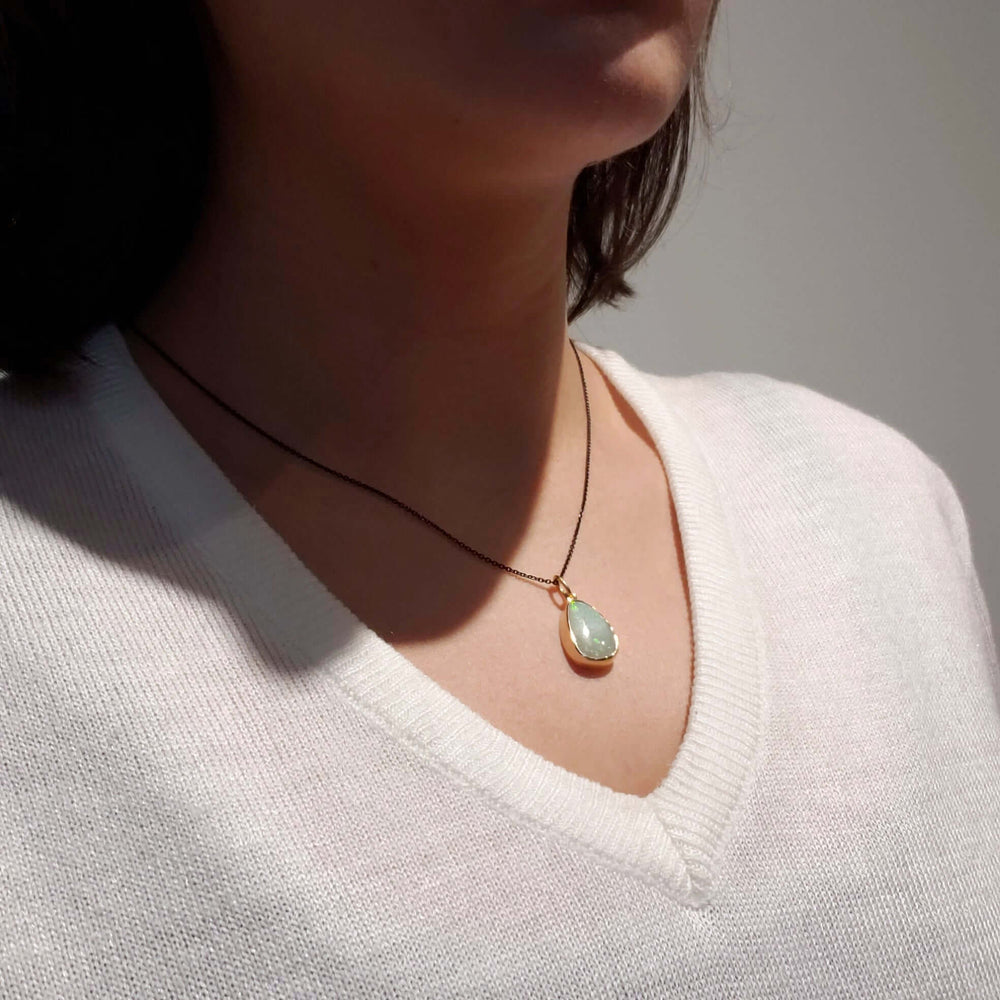 Vintage opal bezel pendant in 14kt yellow gold worn on a black chain