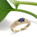 Vintage sapphire and diamond pinky ring in yellow gold beside a green leaf