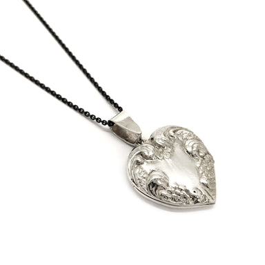 Vintage sterling silver heart locket with embossed floral details on a black chain