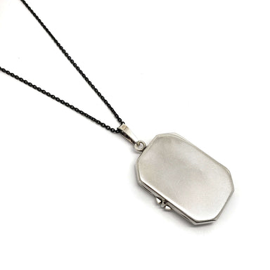 Vintage sterling silver locket on a black chain, closed back view
