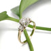 Vintage three-stone diamond ring with yellow gold band and white gold setting, on leafy background