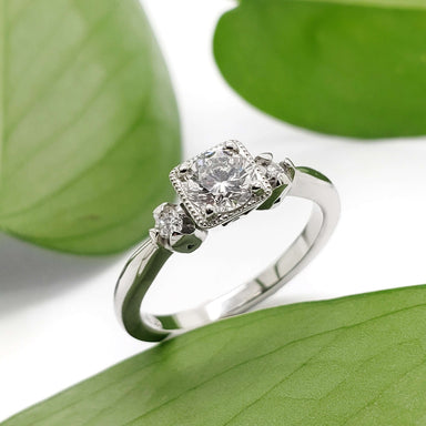 White gold antique diamond engagement ring displayed on green leaves