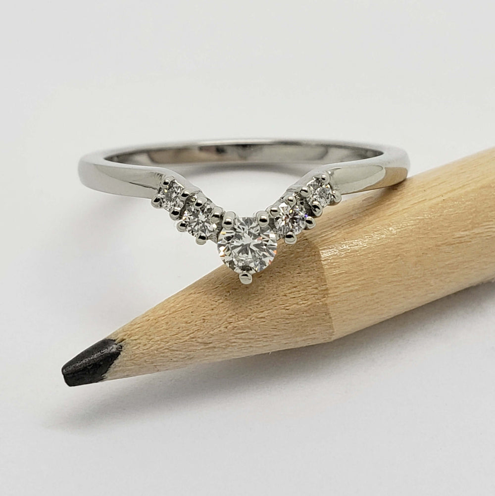 White gold chevron wedding ring with diamonds shown next to a pencil