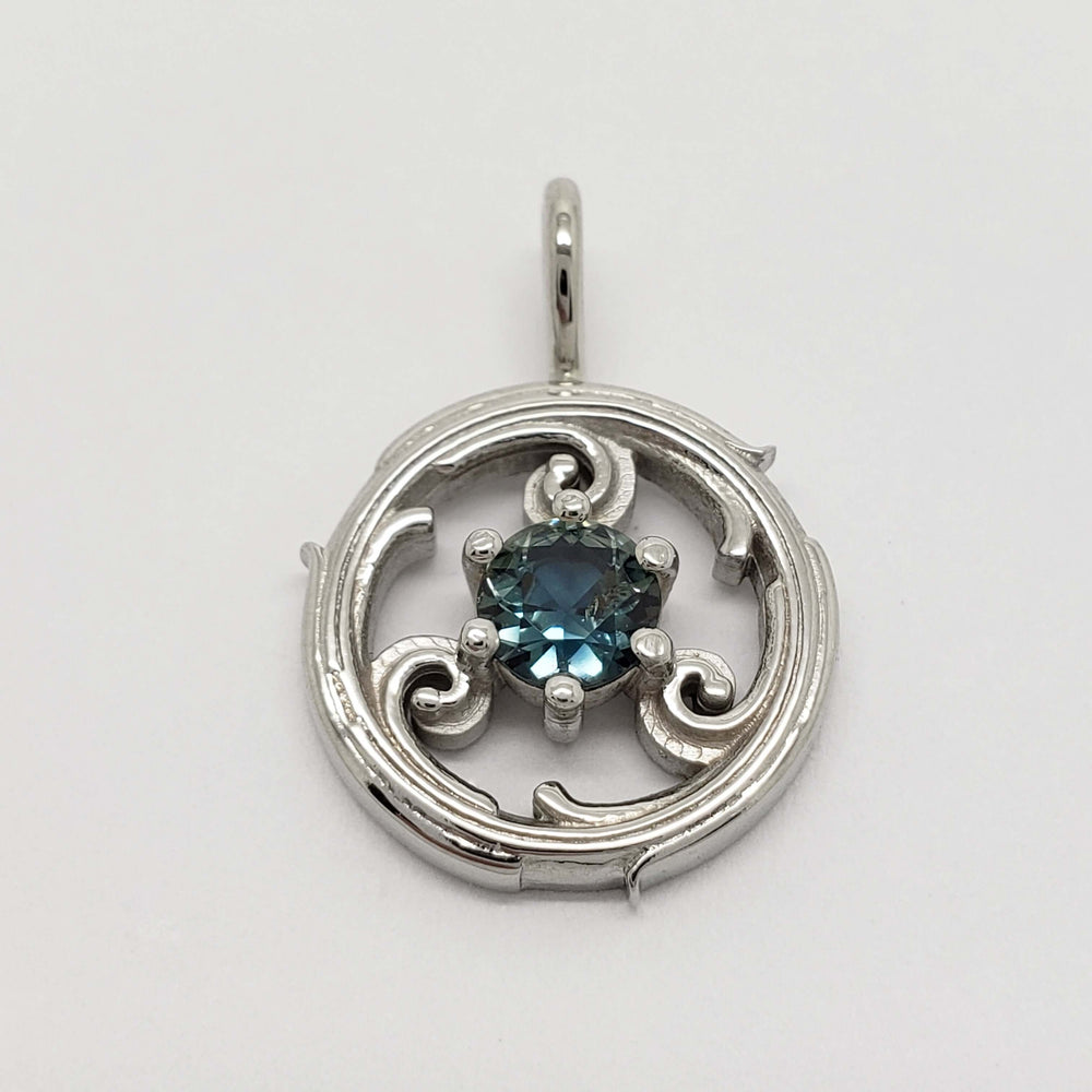 Close-up of a white gold circle vine pendant with a round blue sapphire.