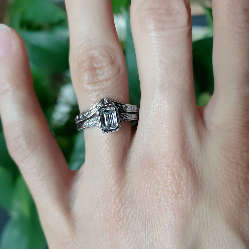 White gold emerald cut lab diamond engagement ring stacked with chevron wedding band, on hand