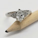 White gold engagement ring with oval lab grown diamond and pave-set side stones, shown with pencil