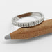 White gold floral millgrain wedding ring displayed on a pencil