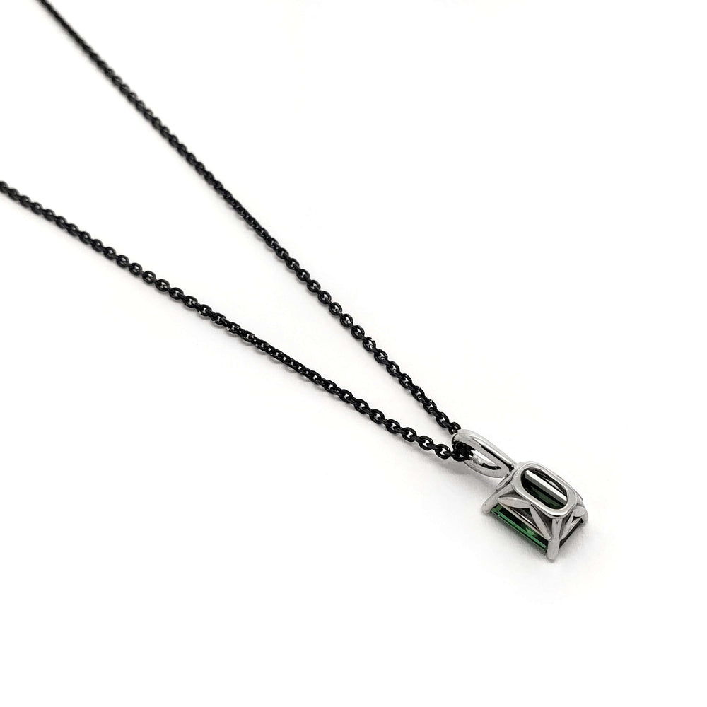 Side view of emerald cut green tourmaline pendant in white gold on a black chain
