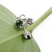Close-up of green tourmaline stud earrings in white gold crown settings on a leaf