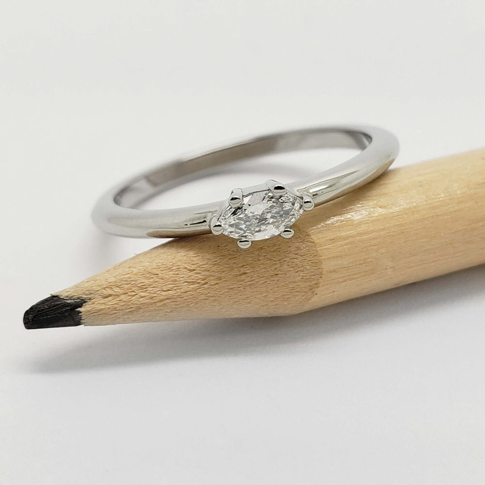 White gold marquise lab diamond ring shown on a pencil for scale