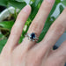 White gold sapphire and diamond engagement ring stacked with leaf-inspired band on hand
