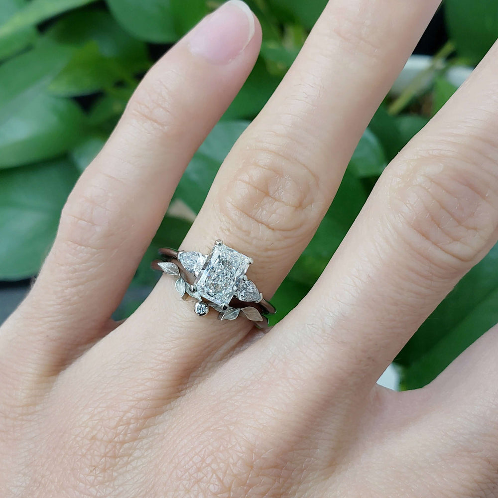 White gold three-stone lab diamond engagement ring stacked with a leaf-inspired band
