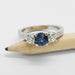 White gold three-stone ring with teal Montana sapphire and diamonds, shown on a pencil