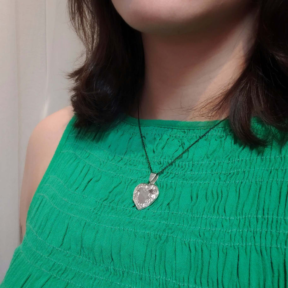 Woman wearing vintage sterling silver heart locket necklace with floral details