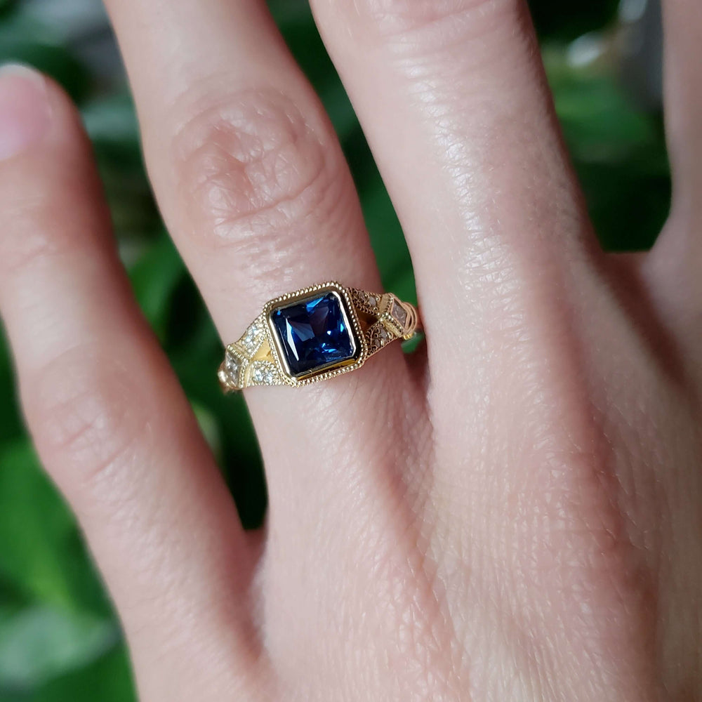 Wren engagement ring with blue sapphire and diamonds worn on hand
