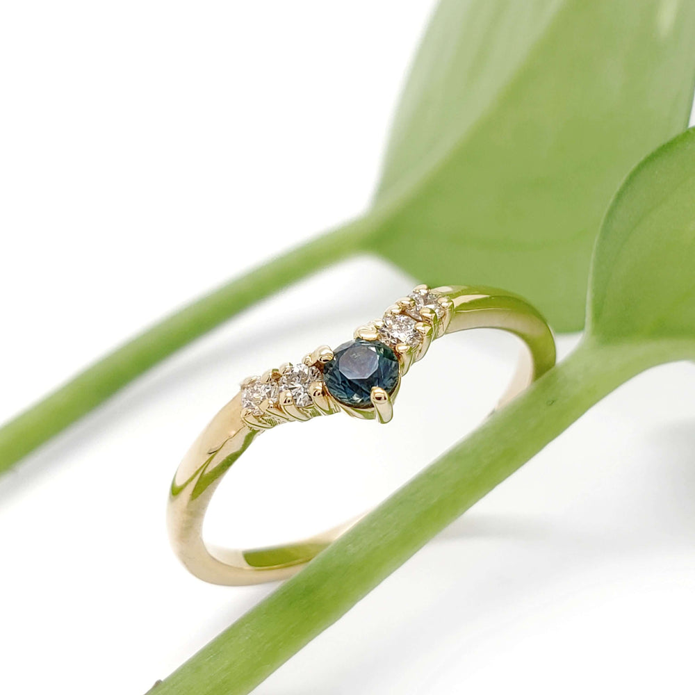 Yellow gold Montana sapphire and diamond ring displayed on green leaves
