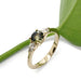 Handcrafted yellow gold ring with Montana sapphire and lab diamonds beside a green leaf