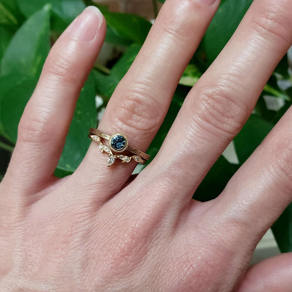 Yellow gold Montana sapphire ring stacked with diamond contour band on hand