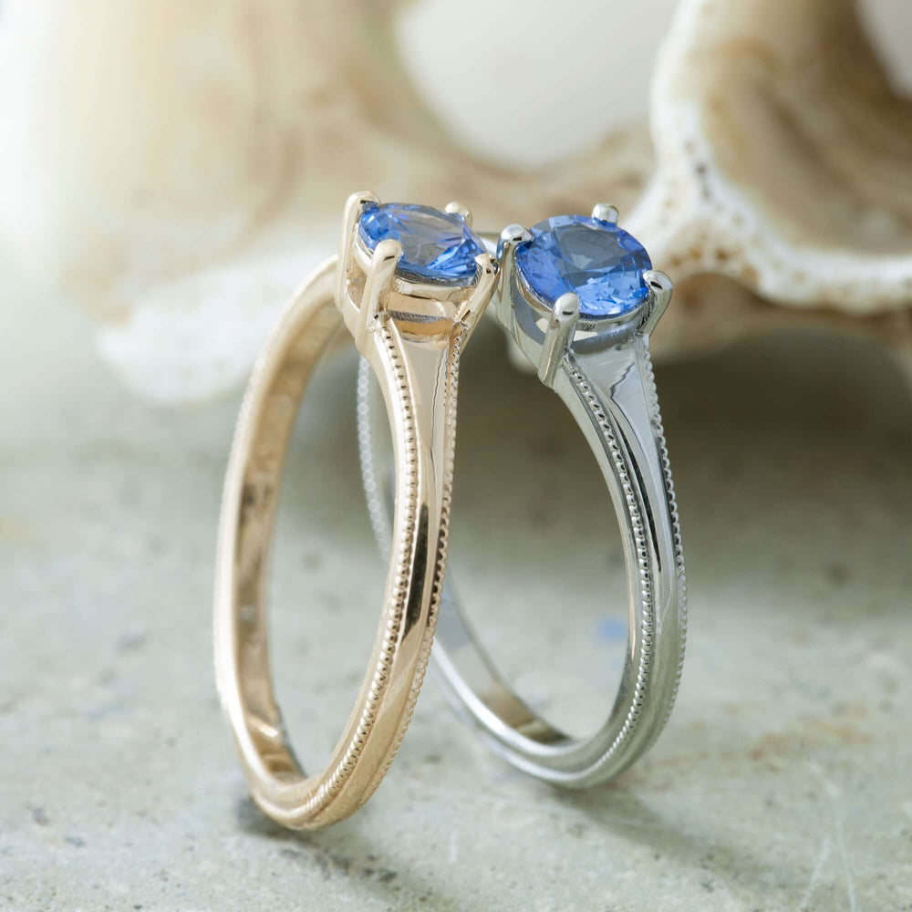 Two solitaire engagement rings with blue sapphires, one in yellow gold and one in white gold