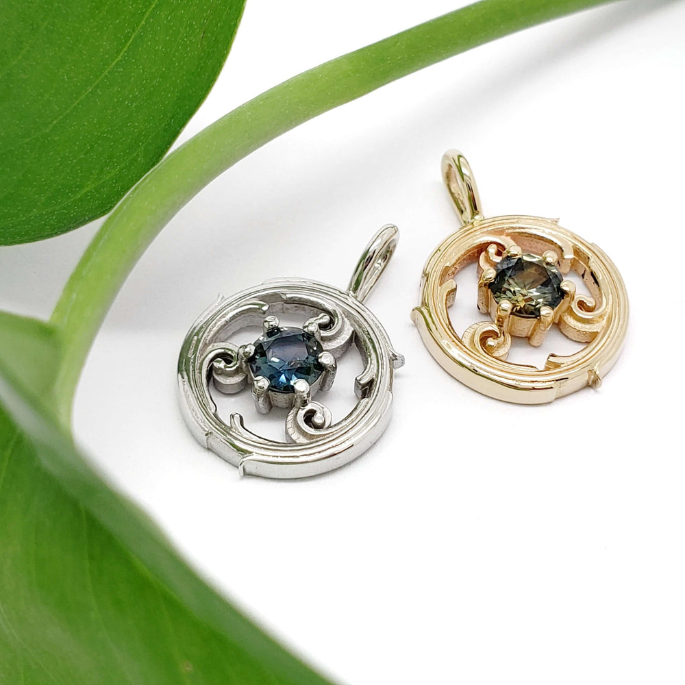 Yellow gold and white gold circle vine sapphire pendants displayed with a green leaf.
