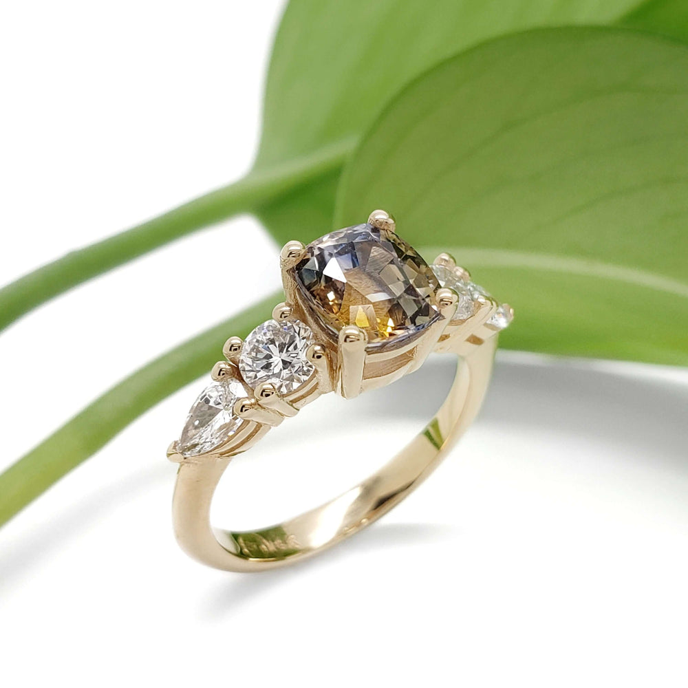 Bi-colour sapphire and lab diamond ring in yellow gold, shown with green leaf background