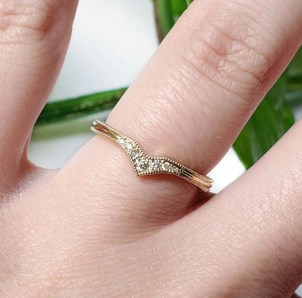 14k yellow gold chevron diamond wedding band worn on a hand