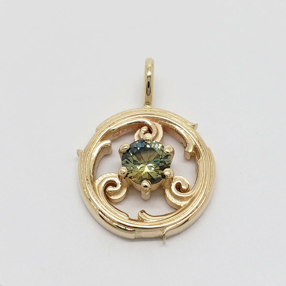 Close-up of a yellow gold circle vine pendant with a round bi-colour sapphire.