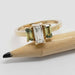 14kt yellow gold engagement ring with baguette diamond and sapphires next to a pencil